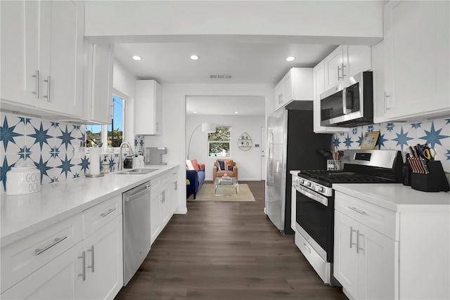 kitchen with white cabinets, visible vents, decorative backsplash, stainless steel appliances, and a sink