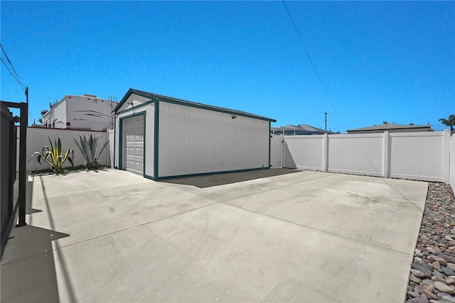 exterior space with fence, an outbuilding, and a detached garage