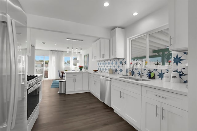 kitchen featuring white cabinets, a sink, light countertops, appliances with stainless steel finishes, and a peninsula