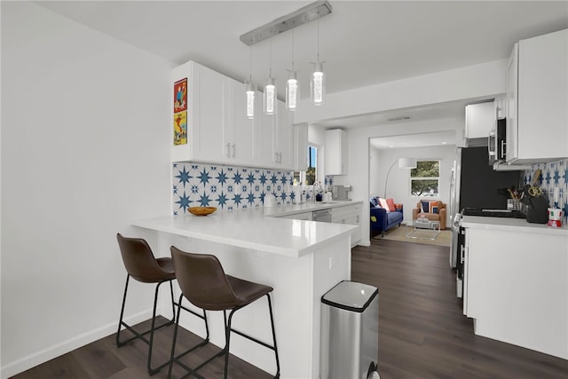 kitchen featuring white cabinets, a breakfast bar, dark wood-style flooring, light countertops, and backsplash