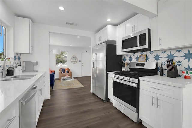 kitchen with dark wood-style floors, visible vents, decorative backsplash, stainless steel appliances, and a sink