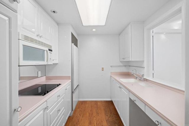 kitchen featuring a sink, white microwave, recessed lighting, white cabinetry, and black electric cooktop