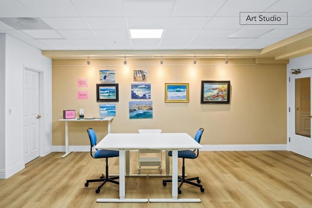 office featuring rail lighting, wood finished floors, baseboards, and a paneled ceiling