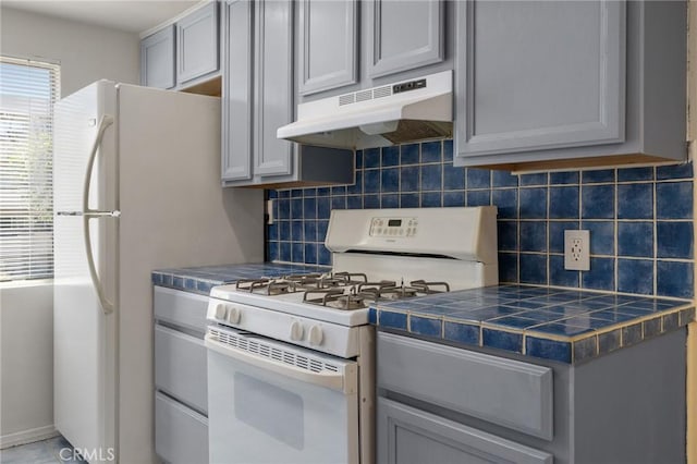 5055 Coldwater Canyon Ave Unit 105, Sherman Oaks, CA 91423 - kitchen featuring white appliances, under cabinet range hood, gray cabinets, tasteful backsplash, and tile counters