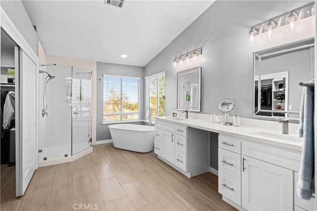 full bathroom with a sink, double vanity, a stall shower, and vaulted ceiling