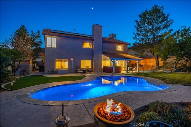 pool featuring a yard, a fire pit, a patio, and a hot tub
