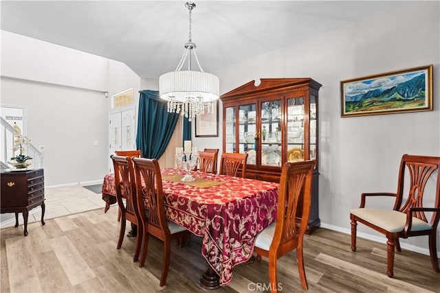 dining space with light wood-style flooring, a chandelier, and baseboards