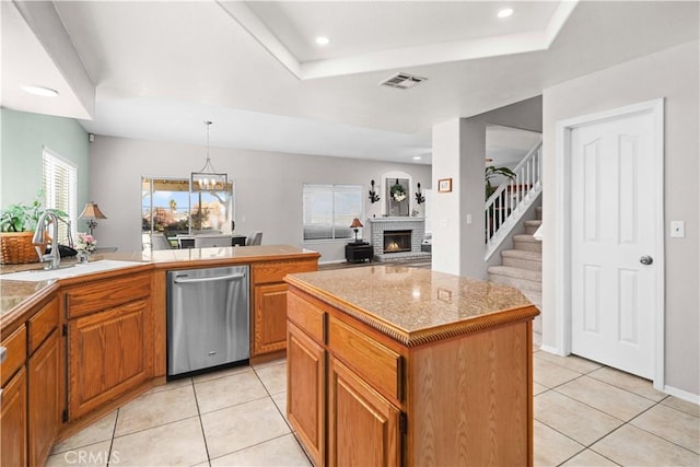 kitchen with visible vents, dishwasher, a fireplace, brown cabinets, and light tile patterned flooring