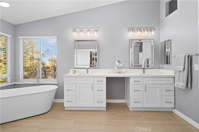 bathroom with baseboards, a soaking tub, vanity, tile patterned floors, and lofted ceiling