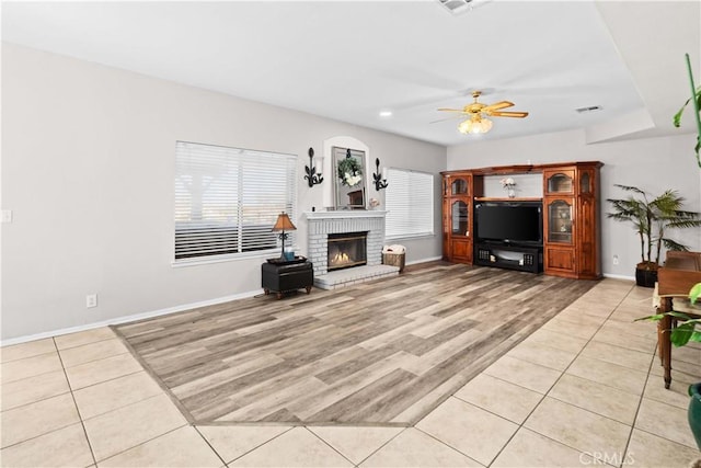 living room with a fireplace, baseboards, a ceiling fan, and light tile patterned flooring