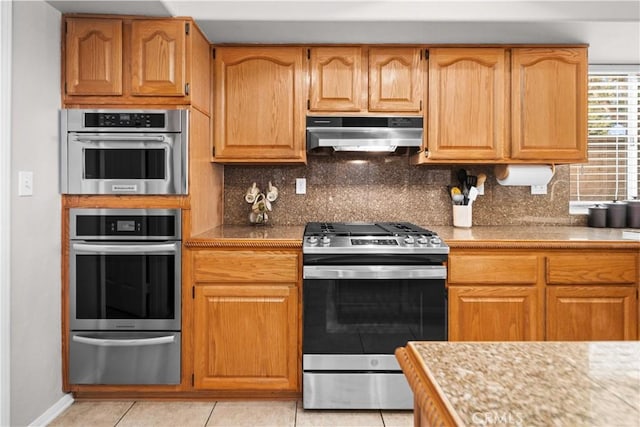 kitchen featuring stainless steel appliances, decorative backsplash, a warming drawer, and ventilation hood