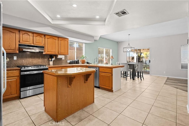 kitchen featuring a peninsula, visible vents, a kitchen island, under cabinet range hood, and stainless steel appliances