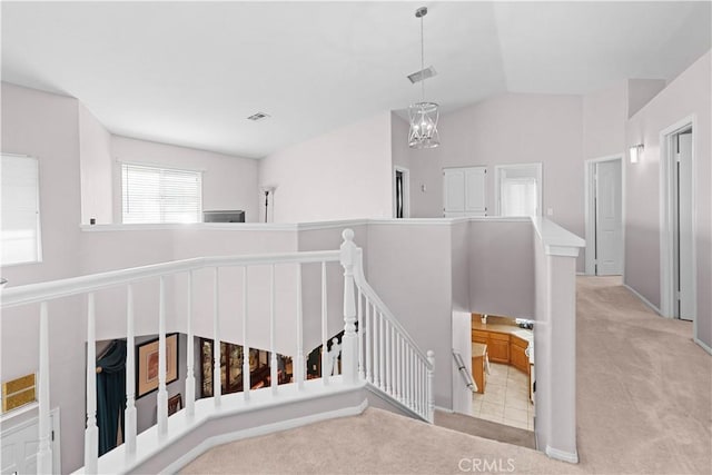 stairs featuring carpet flooring, visible vents, vaulted ceiling, and an inviting chandelier