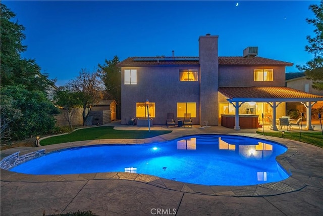 outdoor pool with a jacuzzi, a fenced backyard, and a patio