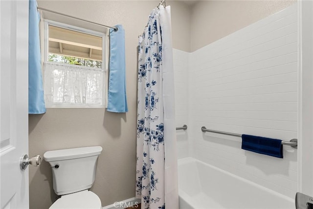 full bath featuring shower / tub combo, toilet, and baseboards