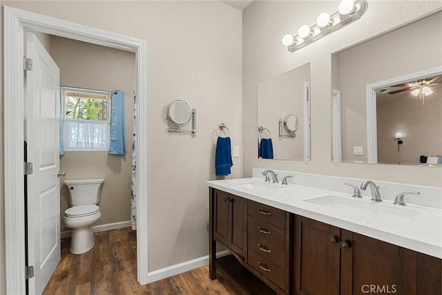 bathroom featuring wood finished floors, double vanity, a sink, and baseboards