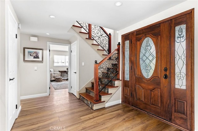 entryway featuring recessed lighting, baseboards, stairway, and light wood-style floors