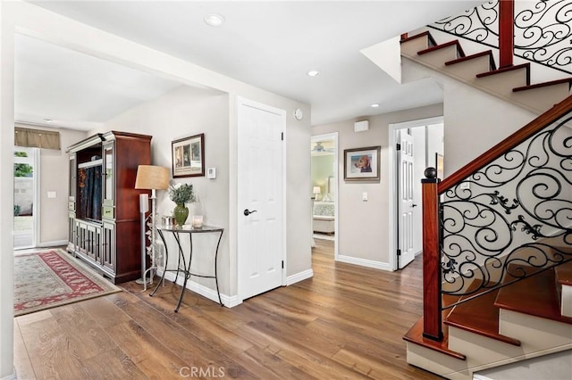 foyer featuring wood finished floors, recessed lighting, baseboards, and stairway