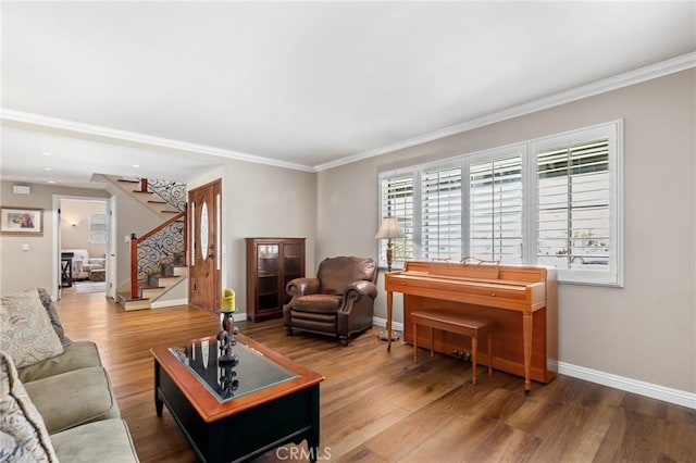 living area featuring wood finished floors, baseboards, ornamental molding, and stairway