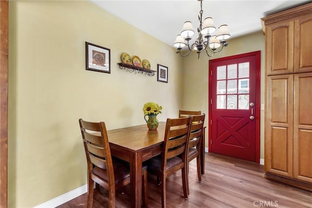dining area featuring a notable chandelier, baseboards, and wood finished floors