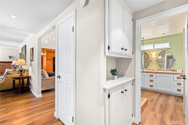 corridor with recessed lighting, light wood-style floors, baseboards, and crown molding