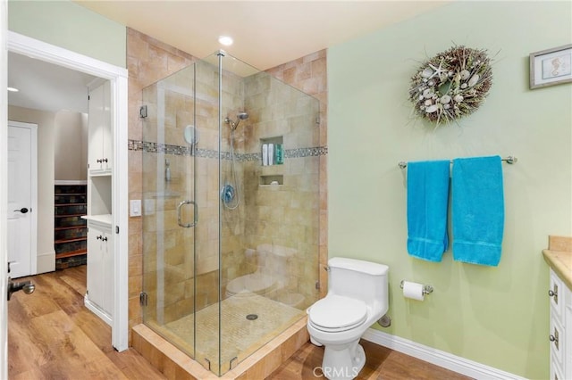 full bath featuring toilet, a shower stall, vanity, and wood finished floors