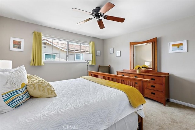 bedroom featuring light colored carpet, baseboards, and a ceiling fan