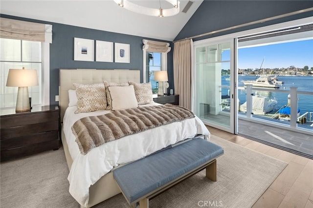bedroom with a water view, access to outside, vaulted ceiling, and wood finished floors