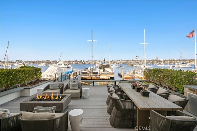 wooden terrace featuring a water view and an outdoor fire pit
