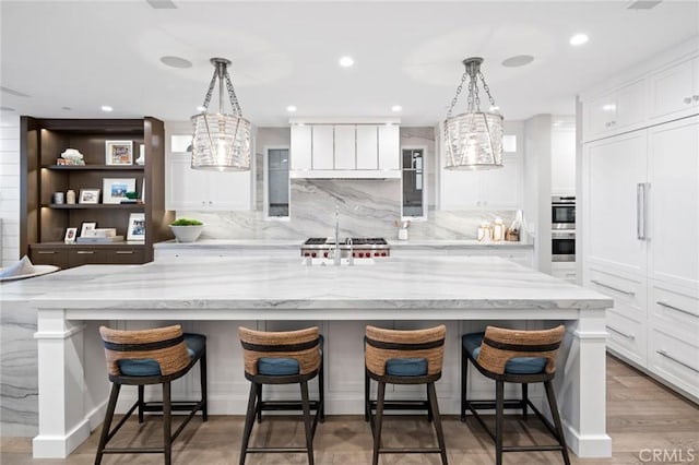 kitchen with double oven, a notable chandelier, white cabinetry, and backsplash