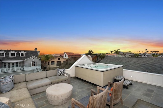 patio terrace at dusk featuring outdoor lounge area, a residential view, a balcony, and a hot tub