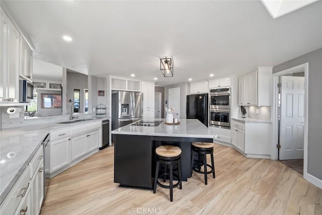 kitchen featuring white cabinetry, light wood-type flooring, black appliances, and a kitchen bar