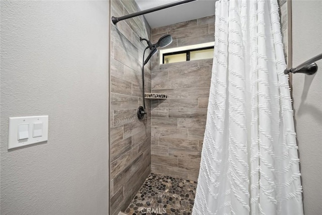 full bathroom with a textured wall and a tile shower