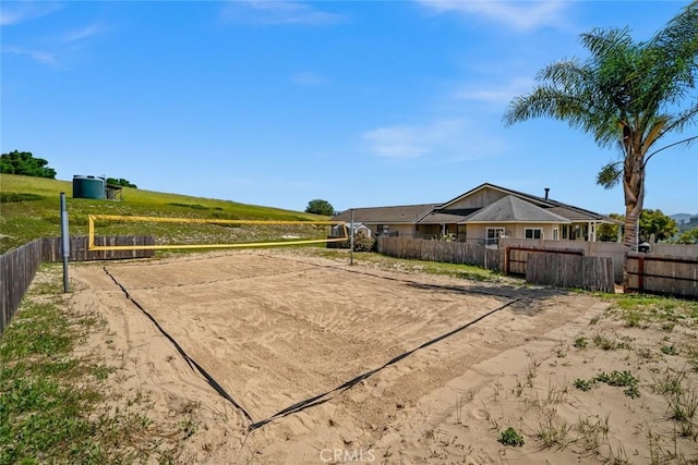 view of home's community with fence, volleyball court, and driveway
