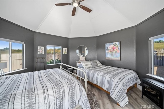 bedroom featuring wood finished floors, ceiling fan, multiple windows, and high vaulted ceiling