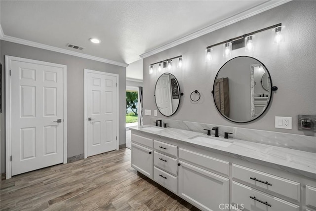 full bathroom featuring crown molding, wood finished floors, a sink, and visible vents