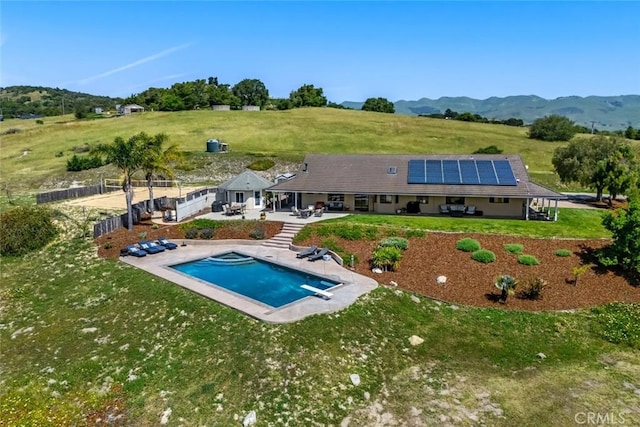 pool featuring a mountain view, a diving board, a patio area, a lawn, and a fenced backyard