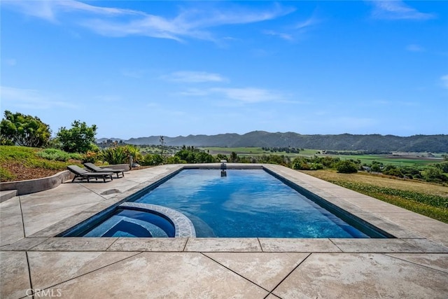 view of swimming pool featuring a mountain view, a pool with connected hot tub, and a patio area