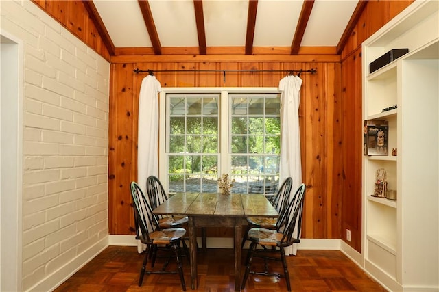 dining area featuring brick wall, wood walls, baseboards, and lofted ceiling with beams