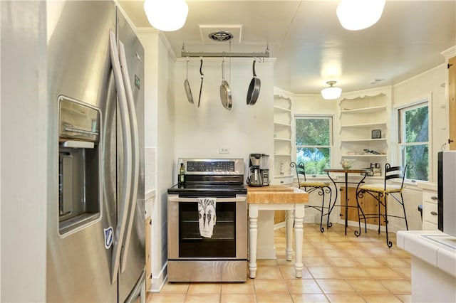 kitchen featuring crown molding, butcher block counters, open shelves, visible vents, and stainless steel appliances