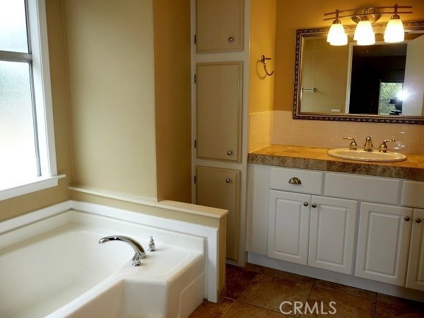 full bath featuring a garden tub and vanity