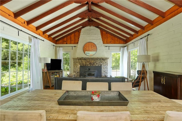 sunroom featuring beamed ceiling and a wood stove