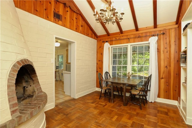 dining room with visible vents, an inviting chandelier, lofted ceiling with beams, a wood stove, and wooden walls