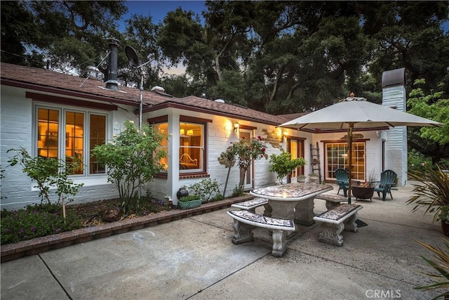 rear view of house with a patio, a chimney, and a fire pit