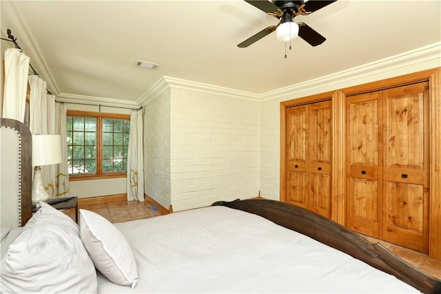bedroom featuring visible vents, two closets, brick wall, ornamental molding, and a ceiling fan