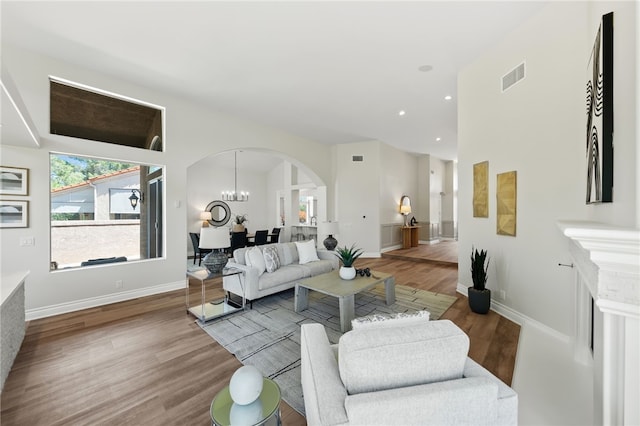 living room featuring arched walkways, baseboards, visible vents, recessed lighting, and wood finished floors