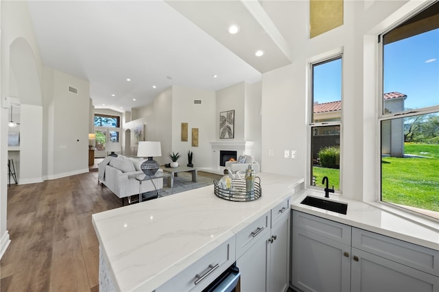 bar featuring wood finished floors, a sink, a glass covered fireplace, visible vents, and recessed lighting