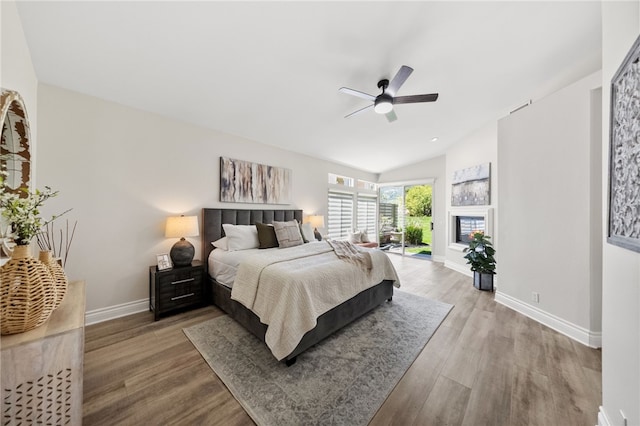bedroom with lofted ceiling, wood finished floors, a ceiling fan, baseboards, and access to outside