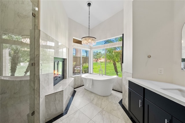 bathroom with a towering ceiling, vanity, a chandelier, a soaking tub, and a stall shower