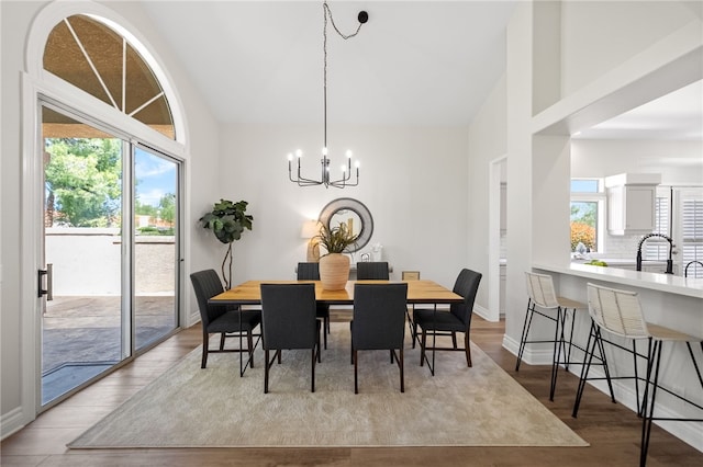 dining area with light wood-style flooring, baseboards, high vaulted ceiling, and a chandelier